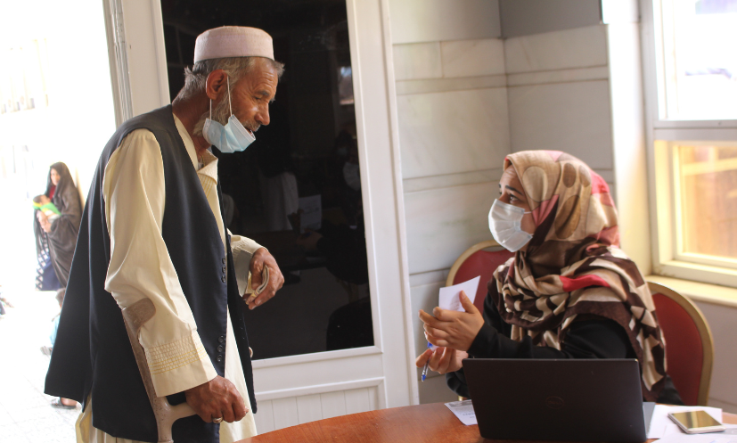 Older man, Hesamuddin, talking with a professional woman in a hijab and face mask 