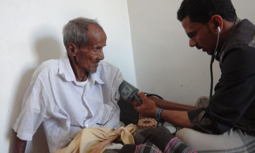 Age International partner takes blood pressure of older man, Yemen