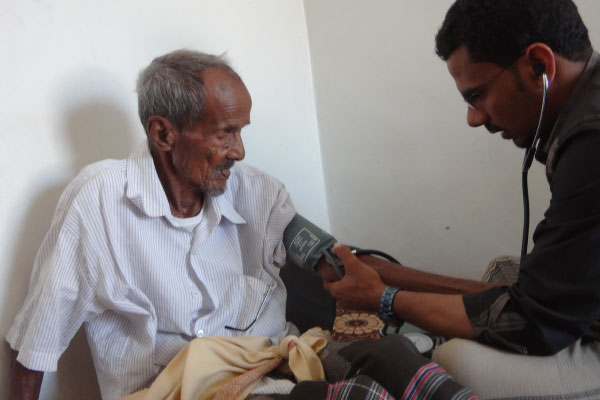 Age International partner takes blood pressure of older man in Yemen