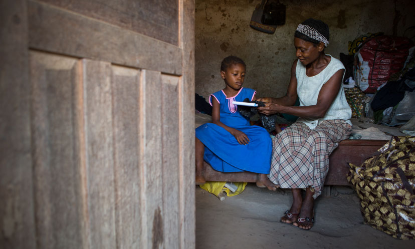 A grandmother gives her granddaughter her school book in Sierra Leone